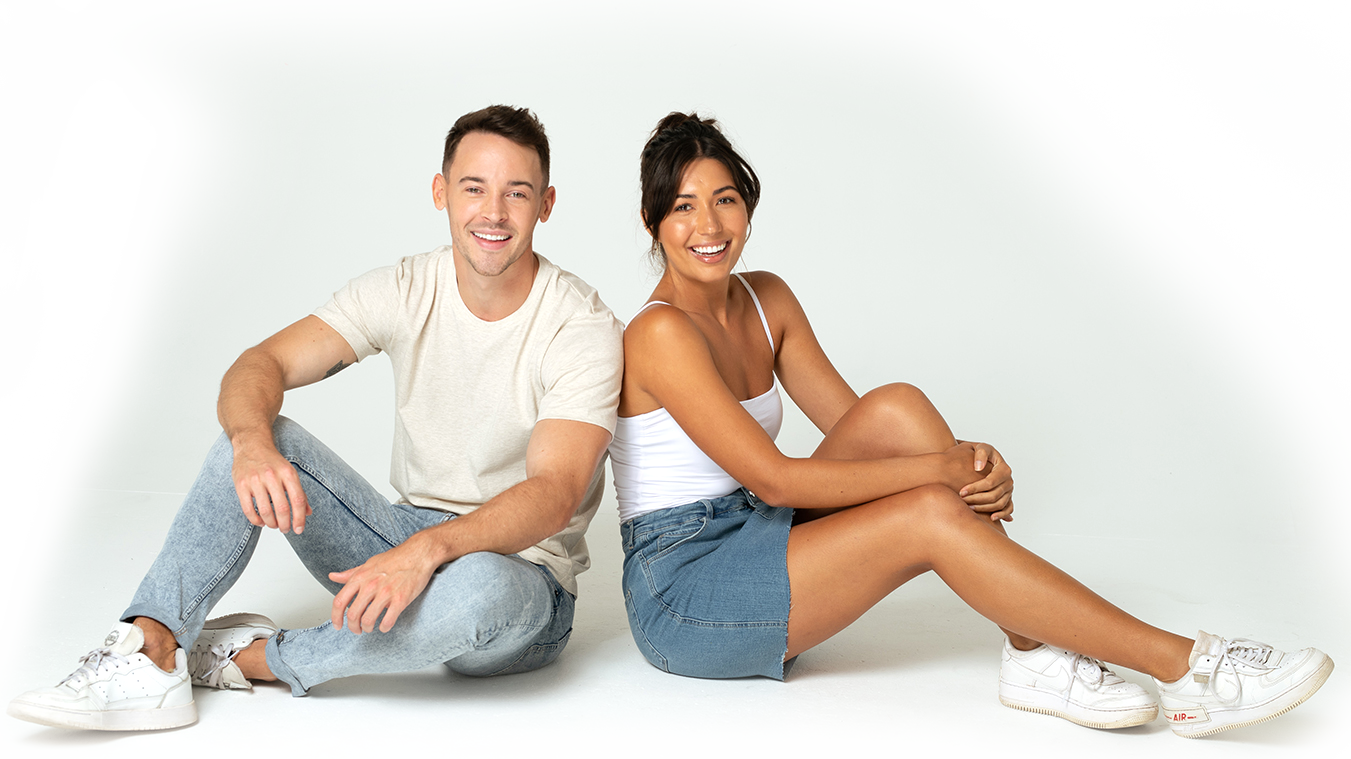 Man and woman sitting back to back, smiling