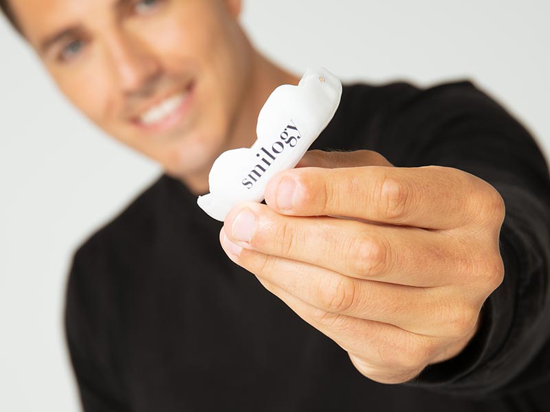 Blurred man holding a white mouthguard forward