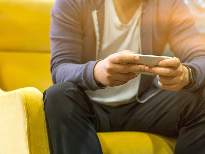 Image of man sitting on couch using his mobile phone