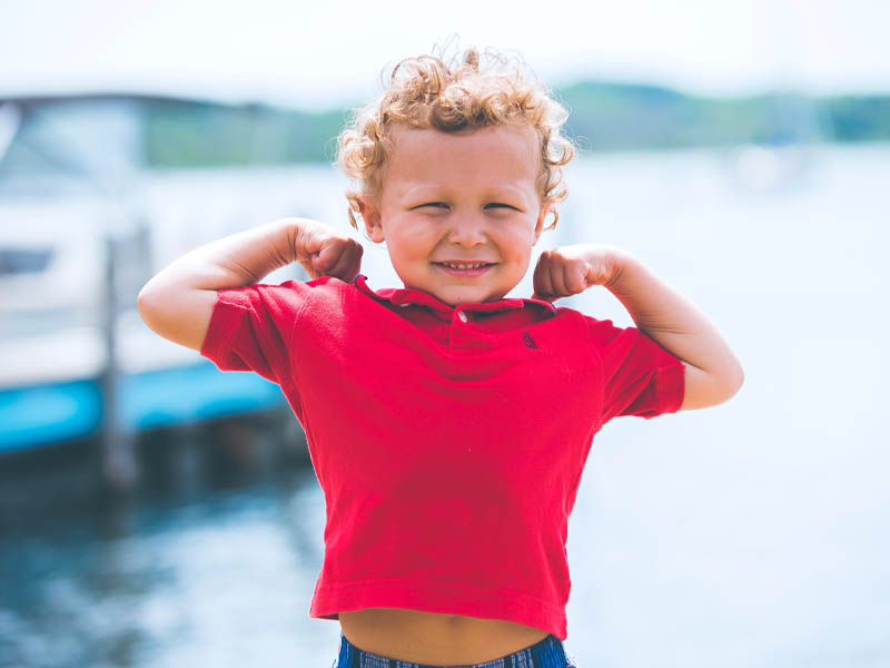 Toddler with arms up showing off his muscles
