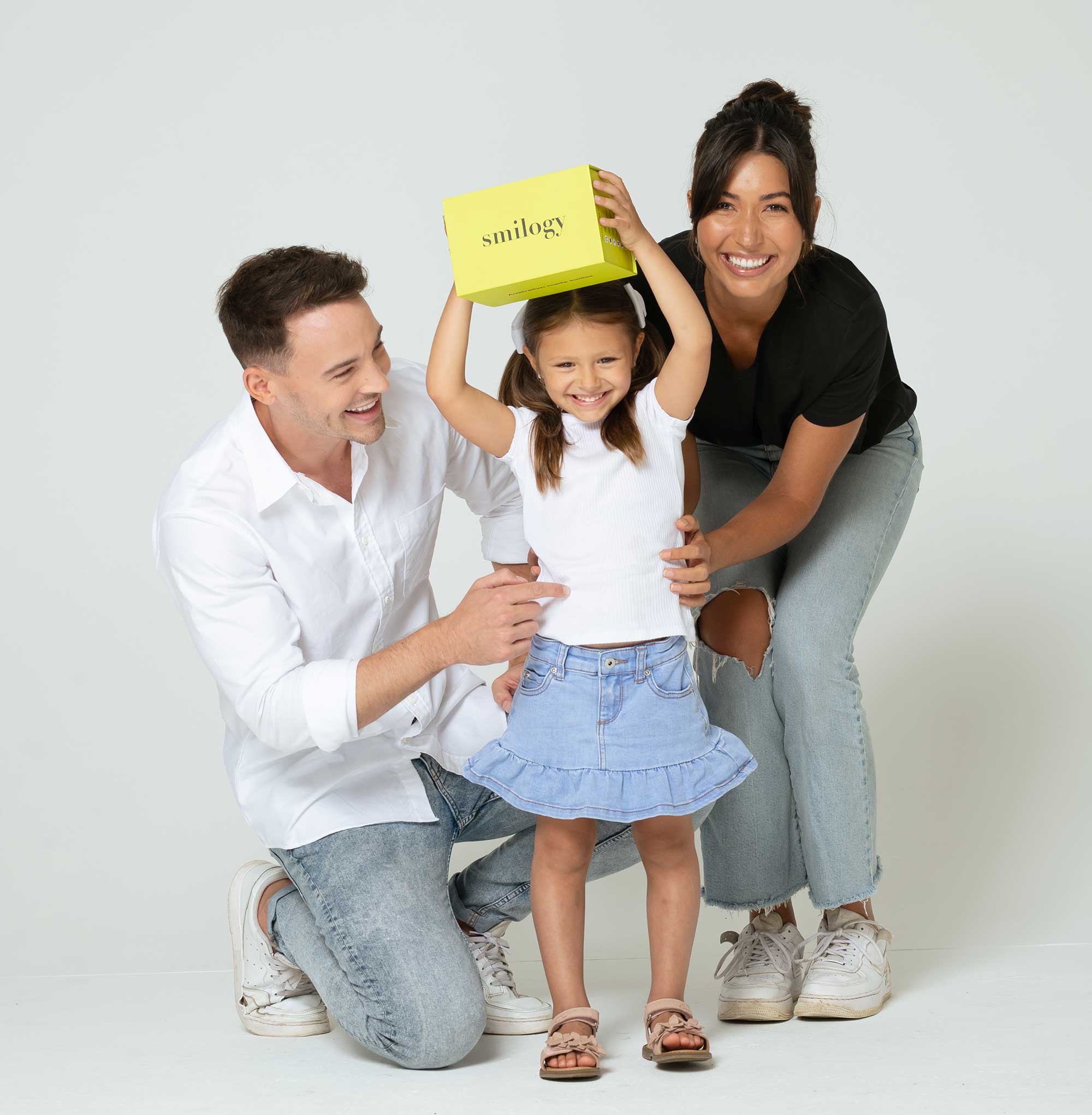 Young family embracing young girl holding smilogy box