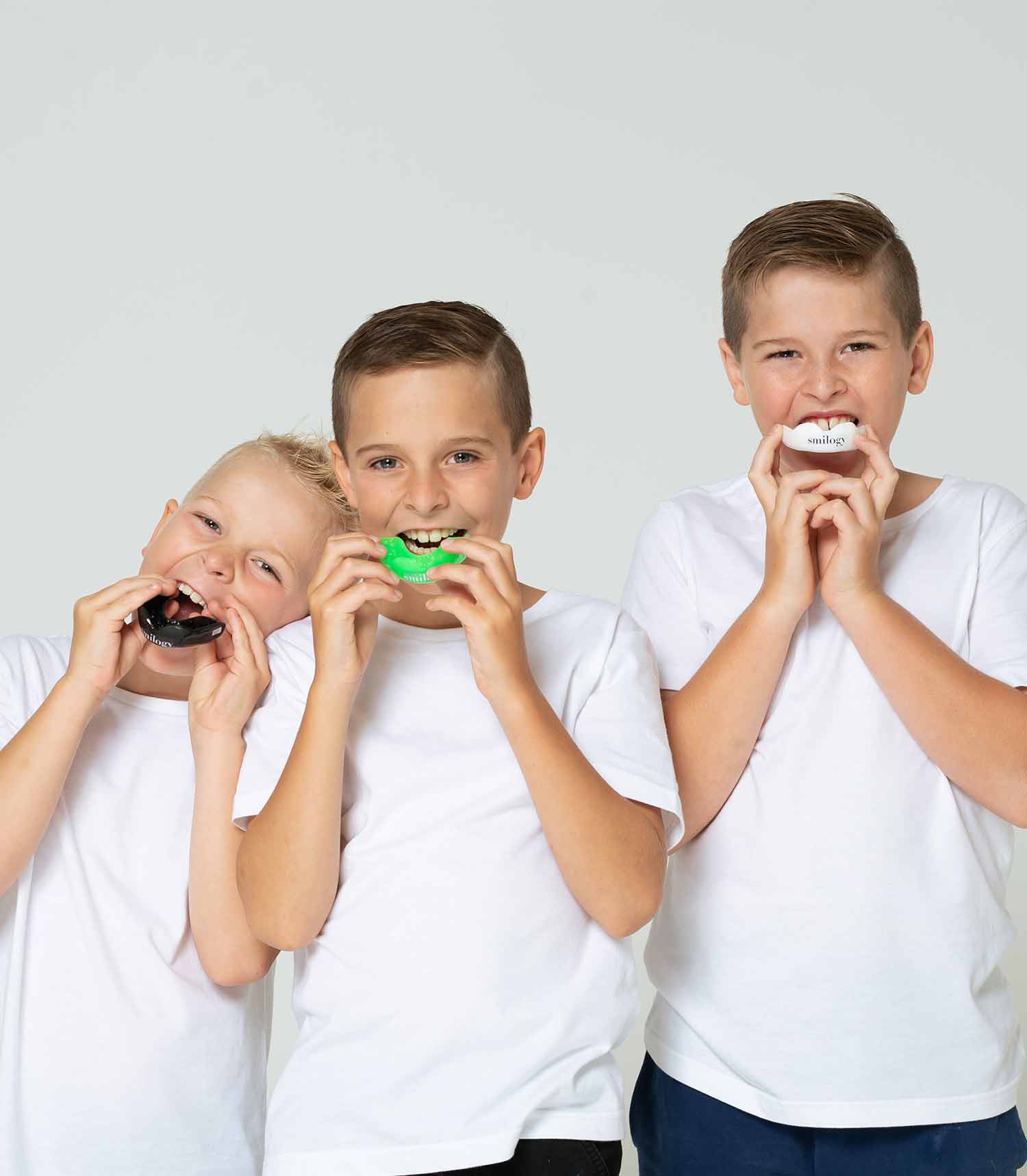 Two young boys wearing mouthguards with their arms linked.