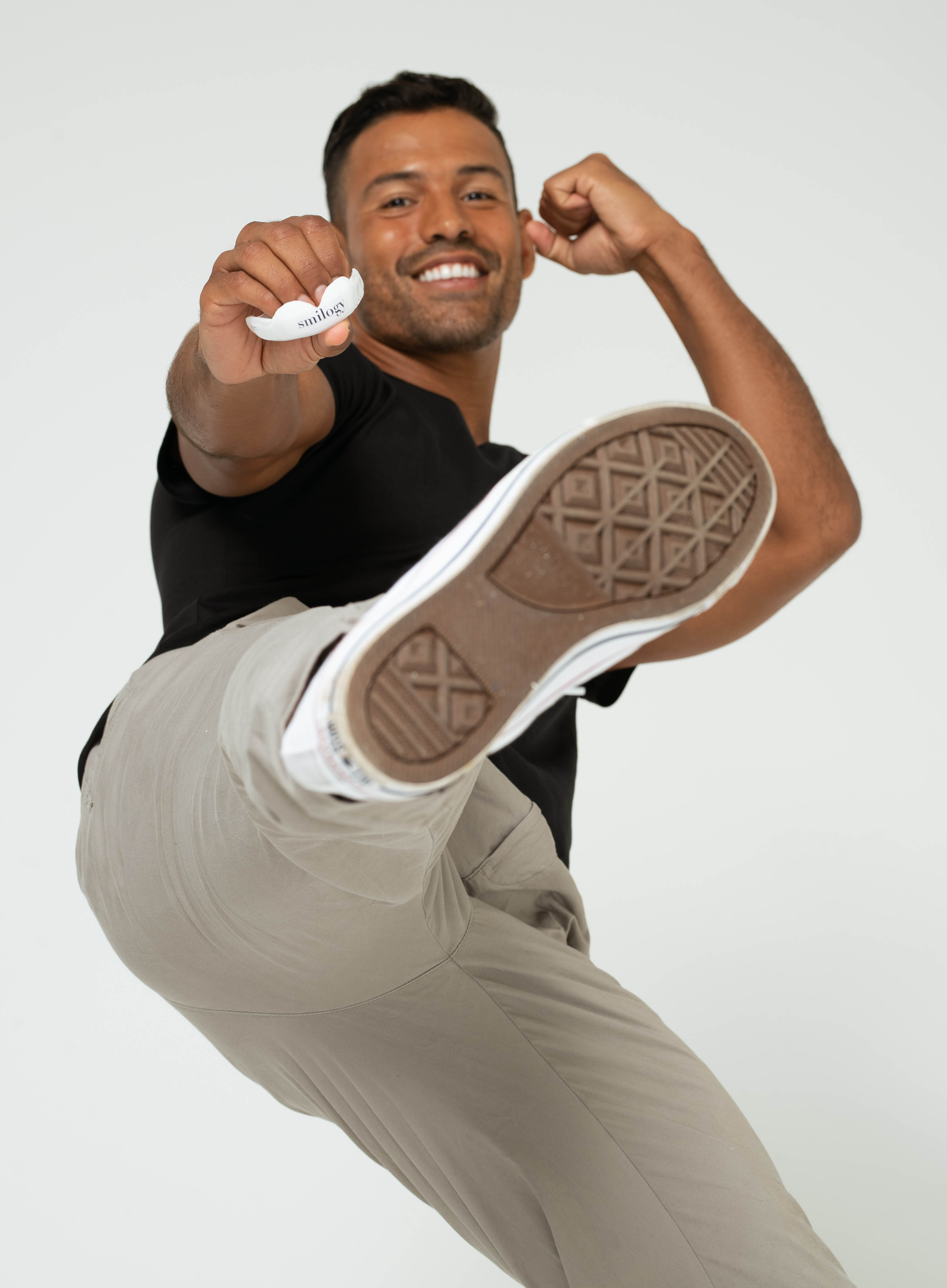 Man doing a front kick holding a mouthguard.