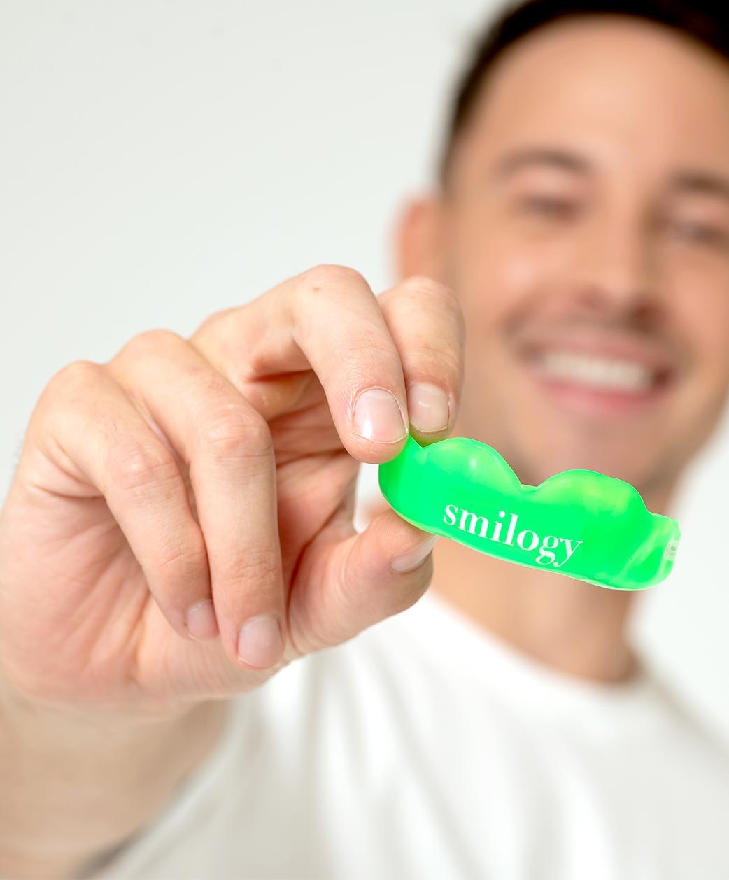 Blurred man holding a bright green mouthguard forward