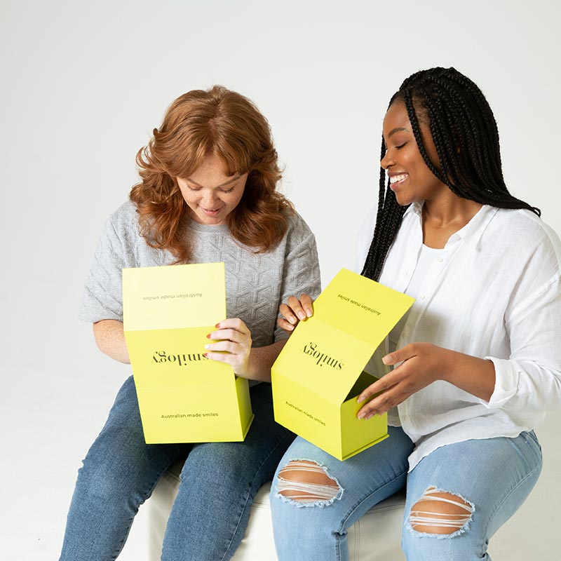 Two women opening smilogy boxes and smiling